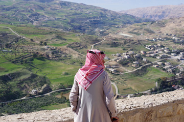Homme avec un chèche regardant la luxuriante vallée depuis la citadelle d'Al Karak, Jordanie - obrazy, fototapety, plakaty