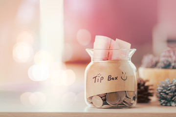 Glass jar with tip box tag and money coins inside