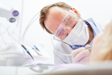 Naklejka premium Dentist with drill in the treatment of patient