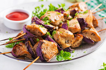 Grilled chicken kebab with red onions on a light table. Grilled meat skewers, shish kebab on light background.