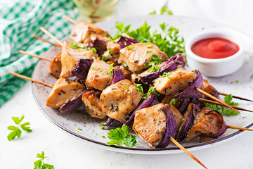 Grilled chicken kebab with red onions on a light table. Grilled meat skewers, shish kebab on light background.