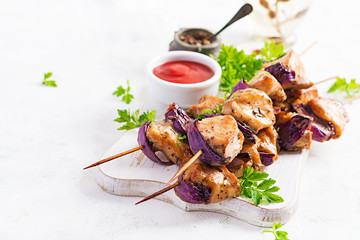 Grilled chicken kebab with red onions on a light table. Grilled meat skewers, shish kebab on light...