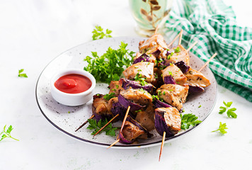 Grilled chicken kebab with red onions on a light table. Grilled meat skewers, shish kebab on light background.