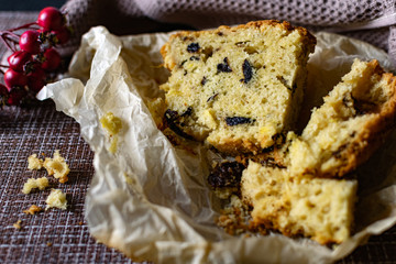 A large piece of homemade pie with prunes filling. orange and Apple, cut on parchment paper. Porous pastry like a cupcake with pieces of berries and fruit, next to delicious crumbs of sponge cake