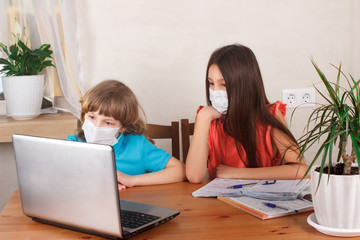 Fototapeta na wymiar Children boy and girl in medical masks on distance education, watching online webinar while quarantine at home. Homeschooling and doing homework, E-learning, web lesson concept