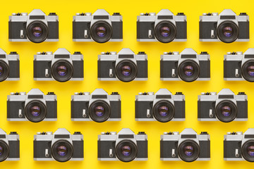 Vintage photo cameras in a row over colorful yellow background