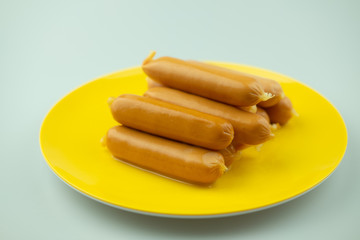 Naklejka na ściany i meble Hot dog sausages on yellow dish