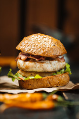 Chicken mini burger on the dark wooden table, upright, side view, closeup