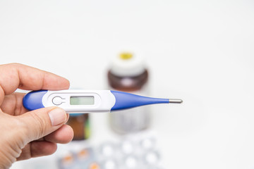 Pills and medical thermometer on white background