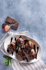 Dessert. Cookies with chocolate topping on a white plate. Anthill. Chocolate, strawberry, mint on a light grey background. Background image, copy space