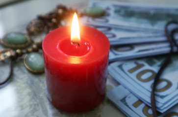 Candle flame on the background of money and amulets, the concept of attracting money
