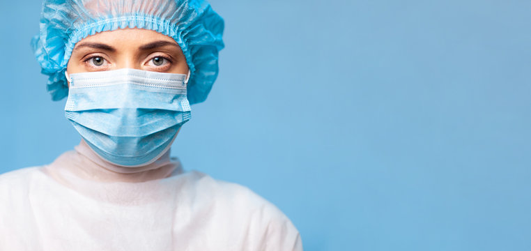female doctor in a protective mask and medical cap, closeup portrait on a blue background. widescreen high resolution image. copy space. empty space for logo or text