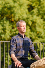 Obraz premium A young man meditates outdoors in a park. 