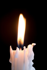 Candleflame on a lit candle.  White candle burning, isolated on a dark background