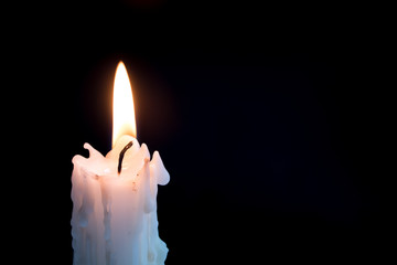 Candleflame on a lit candle.  White candle burning, isolated on a dark background