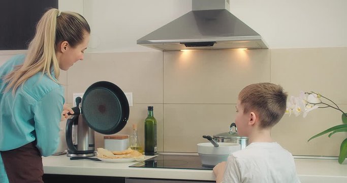 Mother and son preparing food pancakes fried in kitchen at home. Weekend Family Breakfast. 