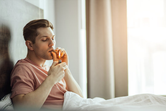 Young Caucasian Man Smoke Cannabis Weed At Home, He Use Lighter, Man Lead Unhealthy Lifestyle. Mariuana, Ganja, Drug, Cannabis, Smoking Concept