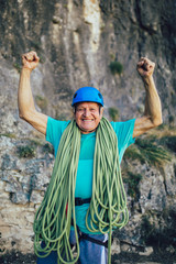 Senior man with a rope preparing for climbing on the rock.