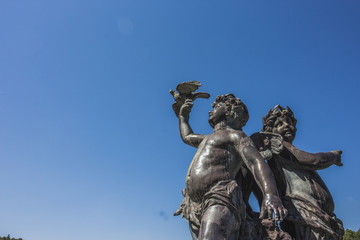 Fototapeta na wymiar Angels statue and blue sky, Sculpture of cupid,The little angel statue holds a bird in his hand.