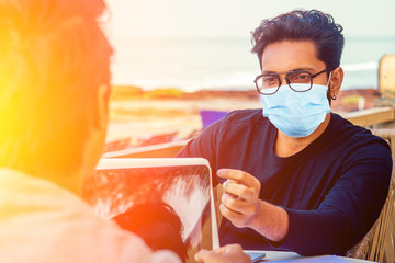 handsome indian man wearing mask and talking with worker colleague . corona virus epidemic and adaptation to new lifestyle