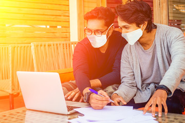 two handsome indian men wearing mask and talking with worker colleague . corona virus epidemic and...