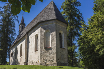 Church in a village with trees around and blue sky.