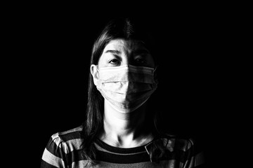 Woman with surgical mask. Pandemic or epidemic and scary, fear or danger concept. Protection for biohazard like COVID-19 aka Coronavirus. Black and White. Black Background