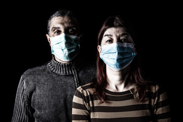 Man and woman with surgical masks. Couple protected with face mask. Pandemic or epidemic, scary, fear or danger concept. Protection for biohazard like COVID-19, Coronavirus, Ebola. Black Background