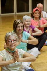 Gruppo di anziani  si dedica allo yoga in palestra