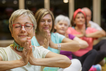 Gruppo di anziani  si dedica allo yoga in palestra