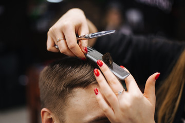 hairdresser cutting hair in barbershop with scissors