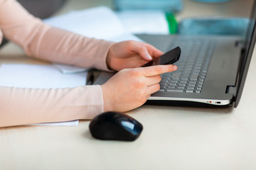 Close up of young school girl working at home in her room with a laptop and class notes studying in a virtual class. Distance education and learning concept during quarantine