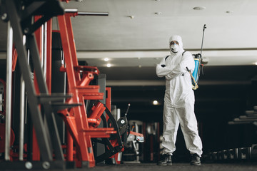 Fototapeta premium Cleaning and Disinfection in crowded places amid the coronavirus epidemic Gym cleaning and disinfection Infection prevention and control of epidemic. Protective suit and mask and spray bag