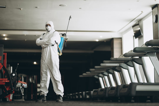 Cleaning and Disinfection in crowded places amid the coronavirus epidemic Gym cleaning and disinfection Infection prevention and control of epidemic. Protective suit and mask and spray bag