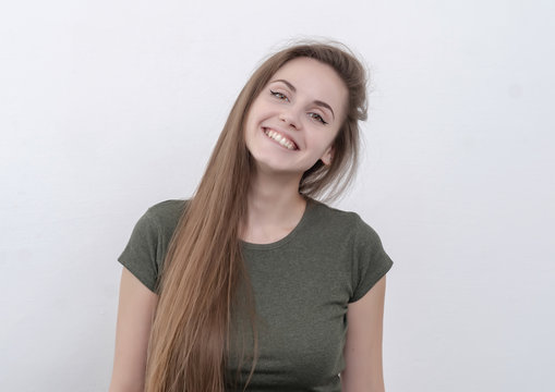 Cheerful ironic girl with long hair smiles at the camera