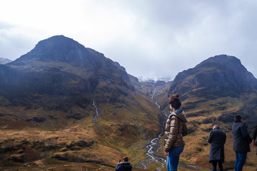 young woman standing on mazing yellow and green mountain landscape watching a city at the horizon
