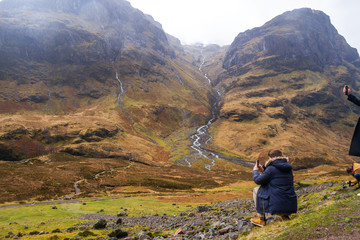 young man standing on mazing yellow and green mountain landscape watching the landscape and taking...