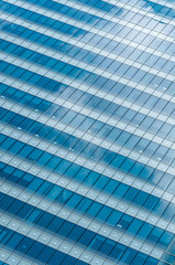 Obraz premium Modern glass facade of office building with reflections of sky