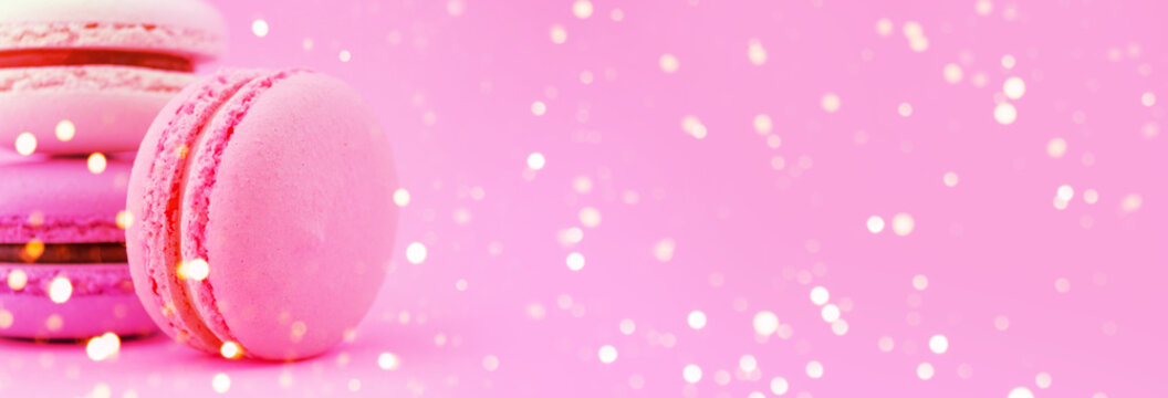 Three pink macaroons on purple background. Horizontal banner. Neon light macro side view concept, copy space