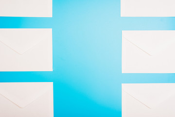 Blue background with white paper envelopes with empty space in the center.