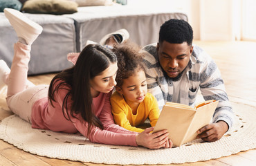 Multiracial family looking at book, stay at home