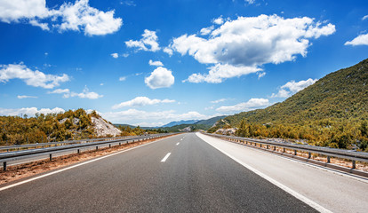 Mountain highway with blue sky and rocky mountains on a background