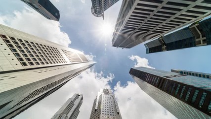 Time-lapse of skyscraper buildings in business district, Singapore city. Cloud on sunny day sky. Low angle view, zoom out. Asia financial economy, merger & acquisition, or modern architecture concept