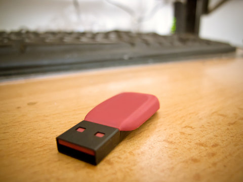 A small flash drive on a wooden office table.