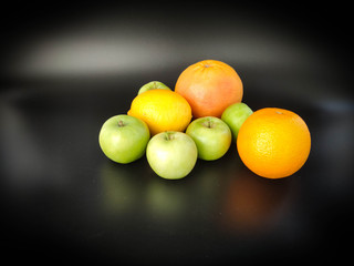Whole fruits green apples, orange, grapefruit and lemon on black background. Concept - vegetarian and healthy food to improve the immunity Stock photo.