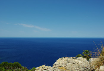 Vivid landscape of Balearic sea's horizon from the Formentor Cape, Mallorca island. Deep blue sea, clear sky, rocks and foliage at the bottom. Background, copyspace. Classic blue. Sunny day.