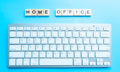 home office work from home concept with letters wooden. And keyboard  next to  background blue