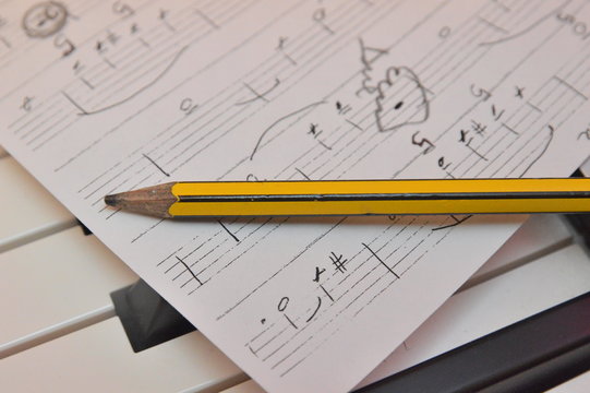 matita su carta musicale su tastiera di pianoforte