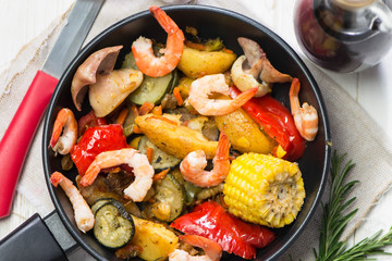 pan with fried vegetables, shrimp and squid with spices
