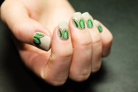 Hands of a young girl with a fashionable manicure vegetable design drawn by hand with a brush gel paints on gel Polish